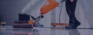 immagine in cui si vedono soltanto le gambe di un addetto alle pulizie echje passano un macchinario industriale per la lucidatura di un pavimento
